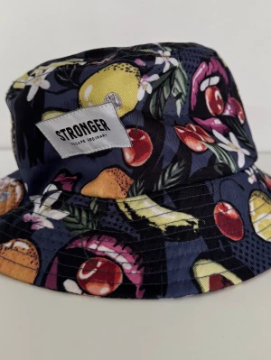 Oanvänd färgglad buckethat från Stronger - Oanvänd färgglad buckethat från Stronger. Det finns inga lappar där storlek står men jag har mätt och uppskattad storlek är cirka 55 cm. Rökfritt hem.