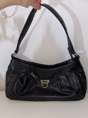 Svart läder väska - En svart läder väska (Inte äkta läder) Accessories by Wedins, den har olika fickor på insidan. Den har en vintage style och passar till alla stilar från sthlm stil till alt-stil osv, Säljer billigt för jag måste göra mig av med allt