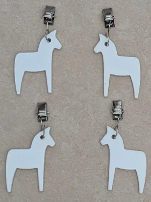 DUKTYNGDER i form av vita hästar - Unika duktyngder i form av vita hästar med silvriga clips. Hästarna har en stilren och minimalistisk design som sticker ut. Perfekta för dig som vill ha något annorlunda och lekfullt.
