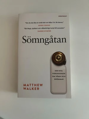 Sömngåtan av Matthew Walker - Sömngåtan är en populärvetenskaplig bok av Matthew Walker som utforskar den senaste forskningen om sömn och drömmar. Boken har ett vitt omslag med svart och röd text samt en illustration av en dörrskylt. Pocketutgåva från Ordfront.