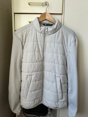 Cardigan från zara  - Snygg ljusgrå pufferjacka från Zara med ståkrage och dragkedja framtill. Jackan har två snedställda fickor och quiltad design. Materialet är mjukt och lätt vadderat, perfekt för kalla vinterdagar. Enkel och stilren look som passar till det mesta.