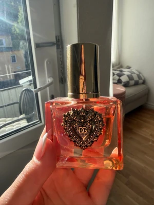 Dolce & Gabbana Devotion INTENSE EdP 30ml - Säljer en Dolce & Gabbana Devotion Eau de Parfum intense i en lyxig, fyrkantig glasflaska med orange ton och guldfärgat hjärtemblem framtill. Flaskan har en elegant guldfärgad kork och rymmer 30ml. Perfekt för dig som gillar exklusiva dofter och snygg design. endast testat