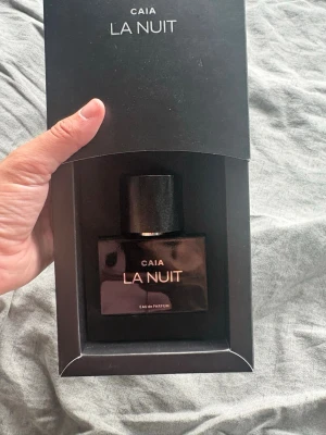 CAIA La Nuit Eau de Parfum - Säljer en elegant parfym från CAIA, La Nuit Eau de Parfum. Flaskan är svart med stilren, fyrkantig form och har guldfärgad text. Kommer i en matchande svart förpackning. Perfekt för dig som gillar exklusiva dofter och snygg design. 55% kvar i flaskan. Nypris full size 595 kr!