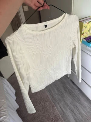Vit ribbad långärmad topp H&M - Säljer en vit långärmad topp från H&M med ribbad struktur och rund halsringning. Toppen har en enkel och stilren design som passar perfekt till jeans eller kjol. Materialet känns mjukt och följsamt mot huden.