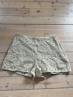 Beige virkade shorts med mönster - Unika beige virkade shorts med detaljerat geometriskt mönster. Perfekta för sommaren och ger en bohemisk vibe till din outfit. Luftiga och bekväma med snygg passform. Midwaist men går att vika ner till low waist om man vill. Använda fåtal gånger
