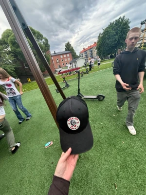 Svart keps med tryck - Säljer en svart keps med rund vit patch framtill där det står 'F*ck Off' och har en röd hand med uppsträckt finger. Kepsen har böjd skärm och justerbar rem bak. Perfekt för dig som vill ha en edgy och personlig stil.