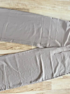 Beige byxa med raka ben - Snygga beige  byxa med raka ben och enkel design. Byxorna har en avslappnad passform och är tillverkade i ett lätt och luftigt linnematerial, perfekt för varma dagar. Fickor på sidorna för en praktisk touch.