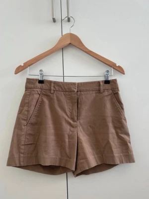 Beiga shorts i bomull och linne - Snygga beiga shorts med normal passform och midja. Gjorda i en skön mix av bomull och linne, perfekta för varma dagar. Klassisk design med sidofickor fram och passpoalfickor bak samt hällor för bälte.