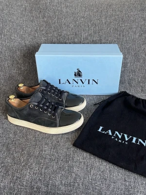 Lanvin skor - Hej, Lanvin skor med lackad captoe i den populära färgen Elephant Grey! Box och dustbag medföljer! I helhet så är skorna i ett gott skick, små flaws finns på ena captoe men är inget märkvärdigt och är lite slitet i hälen. Skulle det vara ett problem så går det att sätta på Leather patches på så är problemet löst. (Finns hos närmsta skobutik/skomakare) :). Skorna har ett nyvärde av 5200kr. Varmt välkommen att höra av dig vid minsta inntresse av köp! Mvh DS 😊