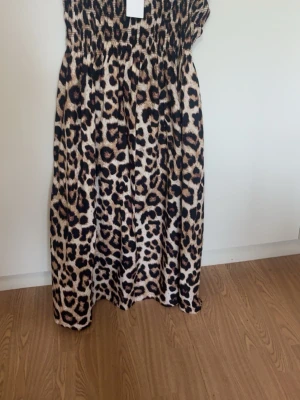 Leopardmönstrad kjol  XL - Leopardmönstrad långkjol med smock i midjan och överdelen.  Färgerna går i beige, svart och bruna toner. Märke: H&M.