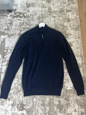 Mörkblå halvzip tröja från Sand - Snygg mörkblå tröja med halv dragkedja i halsen. Material i Merinoull. Perfekt att bära över en t-shirt eller skjorta för en clean och stilren look.