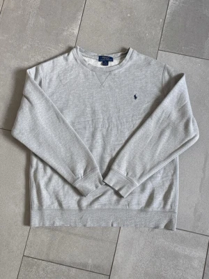 Ralph lauren tröja  - Säljer denna gråa ralph lauren tröjan - Storlek Xl (18-20) passar S - Skick 7/10 (litet hål på armen) - Hör av dig vid minsta fundering!