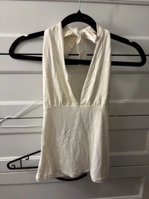 Vit halterneck linnetopp med knyt - Säljer en vit halterneck linnetopp från 15 Collection i storlek M. Toppen har djup v-ringning och knyt i nacken för en snygg och enkel look. Perfekt till sommaren och tillverkad i mjuk bomull för maximal komfort.