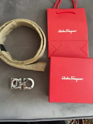 Svart skärp från Salvatore Ferragamo - Snyggt svart skärp från Salvatore Ferragamo i skinn med präglat mönster och en stor, silverfärgad spänne. Perfekt accessoar för att lyfta din outfit. Kommer med originalförpackning och påse.
