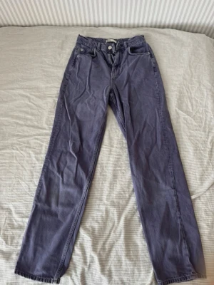 Lila raka jeans  - Säljer ett par lila jeans med rak passform och klassisk femficksdesign. Jeansen har knapp- och dragkedjestängning samt bälteshällor.Perfekta för en avslappnad och trendig look. Den lila färgen är något urtvättad men inget man tänker på. Innerbenslängden är ca 80 cm