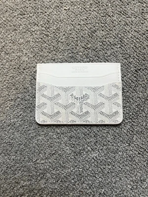 Vit kortplånbok från Goyard - Snygg vit kortplånbok från Goyard med klassiskt mönster och flera kortfack. Plånboken är tunn och smidig, perfekt för att bära med sig i fickan. Tillverkad i läder med Goyards ikoniska tryck framtill.