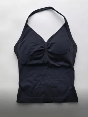 Svart halterneck linnetopp - Snygg svart linnetopp med halterneck och lätt rynkad detalj vid bysten. Toppen är ärmlös och har en figurnära passform och passar som XS-S🥰