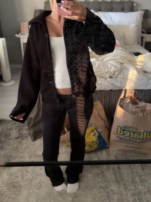 Svart teddyjacka med dragkedja - En svart teddyjacka i fluffigt material med dragkedja framtill och hög krage. Jackan har en avslappnad passform och långa ärmar, perfekt för lager-på-lager och ger en chill vibe till din outfit.