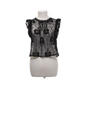 Spetsstopp från ZARA - Snygg svart blus från ZARA i transparent spets med volangdetaljer vid axlarna. Blusen är ärmlös och har ett feminint mönster i spetsen som ger en cool och trendig look. Perfekt att styla med jeans eller kjol för en extra touch.