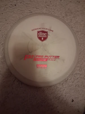 Vit Discmania P2 Pro Putter - Säljer en vit Discmania P2 Pro Putter Disc, Flex 2. Discen har röd text och är tillverkad i plast. Perfekt för dig som gillar discgolf och vill ha en pålitlig putter i samlingen.