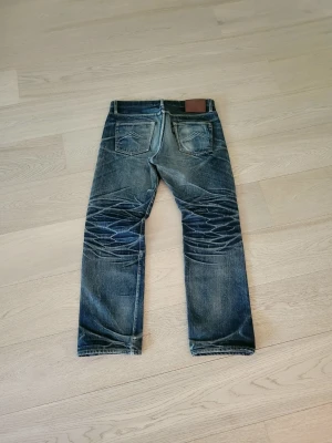Selvedge jeans - Extremt sällsynta selvedge jeans från indonesiska märket Blue Saga.  21oz tyg med sinnesjuka slitningar som tagit många år att skapa!  Storlek: 31/32  Mått:  Midja - 43cm Ytterbenslängd - 100cm Benöppning - 20,5cm  Bara att hojta till vid fler funderingar😊  Sökord: Selvedge Selvage Denim Faded Nudie Raw japaneese bootcut straight a.p.c momotaro archive slitna jeans fullcount strike gold iron heart