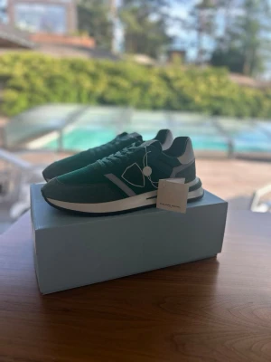 Oanvända Philippe Model 45 Herrskor Grön - Snygga sneakers från Philippe Model i grön mocka, perfekta under sommaren. Skorna har aldrig haft en fot i sig, aldrig klivit ett steg, sprillans nya som ni kan se på den andra bilden. De är självklart äkta och kvitto ingår. Antingen kan ni hämta dem i sollentuna eller så kan jag frakta de med köparskydd. Storleken är 45, de är lite större i storleken. nypris ligger på 3200kr, mitt pris endast 1399kr.