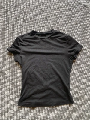 Svart basic t-shirt - En enkel svart t-shirt med rund hals och korta ärmar. Perfekt att matcha med allt och har en klassisk passform. Den är croppad så perfekt för sommaren. Pruta gärna!🥰