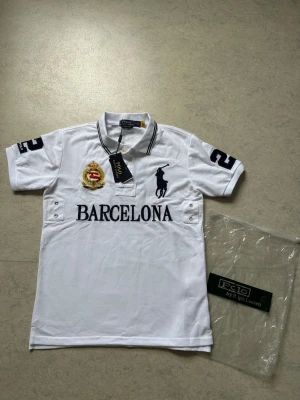 Vit piké från Polo Ralph Lauren - Säljer en Polo Ralph Lauren Barcelona pikétröja – storlek S.  Tröjan är helt ny och oanvänd, i nyskick. Klassisk design med exklusiv Barcelona-brodyr. Väldigt bekväm att bära och perfekt för dig som vill ha en stilren och välklädd look.  Information:  * Märke: Polo Ralph Lauren * Modell: Barcelona * Färg: Vit * Storlek: S * Helt ny och oanvänd * Bekväm passform * Hög kvalitet  Skickas eller hämtas enligt överenskommelse. Hör gärna av dig vid frågor eller intresse!