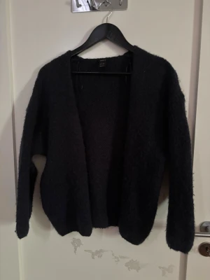 Öppen kofta från Lindex  - Mysig marinblå kofta med öppen front och lång ärm. Tillverkad i ett fluffigt material som ger en avslappnad och trendig look. Perfekt att slänga över en t-shirt eller topp för extra värme. Storlek XS