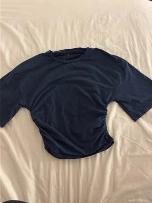 Mörkblå loose t-shirt - En enkel mörkblå t-shirt i loose passform med rund hals och korta ärmar. Tillverkad i mjuk bomull som känns skön mot huden. Perfekt till jeans eller shorts för en avslappnad look. Knappt använd.