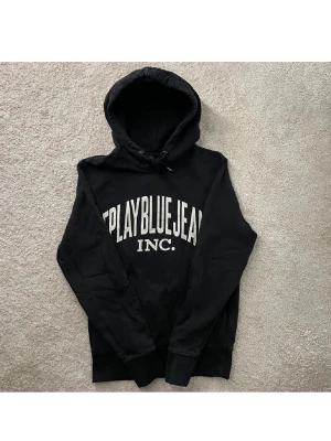 Svart hoodie Replay Blue Jeans - Svart hoodie med vit text 'Replay Blue Jeans INC.' på bröstet. Klassisk huva med snörning och långa ärmar. Perfekt för en avslappnad och cool stil.