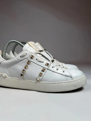  Snygga Valentino open - Snygga vita sneakers från Valentino i läder med  guldfärgade nitar längs sidorna och på hälen. Låg modell med vita skosnören. Även en logga på plösen. De är st 39 men passar för st 40.😁