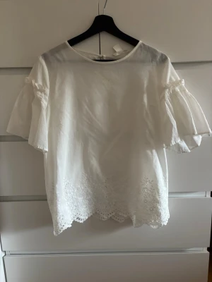Vit blus med broderade detaljer - Söt vit blus som jag använt fåtal gånger. Den kommer ifrån hm och har en väldigt fin passform. Kontakta mig gärna för mer info 