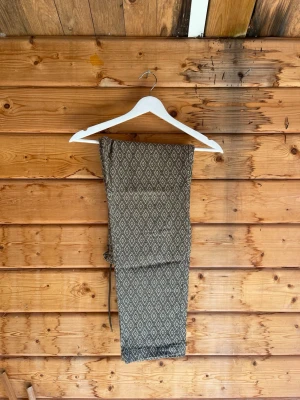 Beige och bruna byxor med mönster - Unika byxor från Stussy i beige och brunt med ett snyggt geometriskt mönster. Byxorna har rak passform och knytband i midjan för extra stilpoäng. Perfekta för dig som vill sticka ut lite extra.