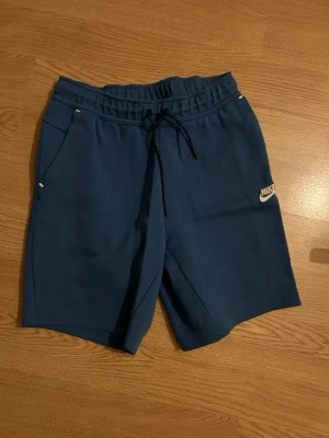 Blå Nike shorts med snörning - Säljer mina blåa Nike tech shorts då de är för små. Inga defekter skriv om ni har frågor.