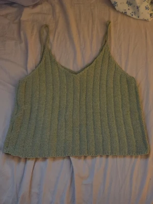 Ljusgrönt stickat linne - Säljer ett ljusgrönt stickat linne från Lofty Style i storlek M. Linnet har smala axelband, v-ringning och är ribbstickat för en snygg struktur. Perfekt för dig som gillar en avslappnad och trendig look. Den har samma form fram och bak