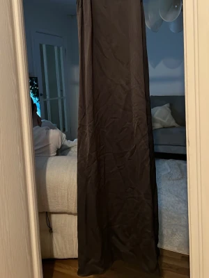 Grå lång klänning i satin - Säljer en elegant grå långklänning i mjukt satinliknande material. Klänningen har en rak och enkel siluett utan synliga detaljer eller mönster, perfekt för dig som gillar minimalistisk stil.