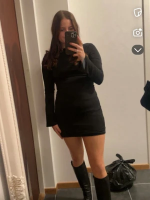 Svart långärmad kortklänning - En stilren svart kortklänning med lång ärm och figurnära passform. Öppen rygg! Använt fåtal gånger. 