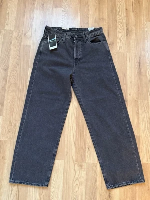 Svarta baggy jeans från Jack & Jones - Snygga svarta baggy jeans från Jack & Jones med klassisk femficksdesign och raka ben. Jeansen har hällor för bälte och knappgylf. Tillverkade i mjuk denim som ger en avslappnad och trendig look. De är helt nya aldrig använda de var lite för små och glömde då att att returnera de så öppetköpet gick ut!