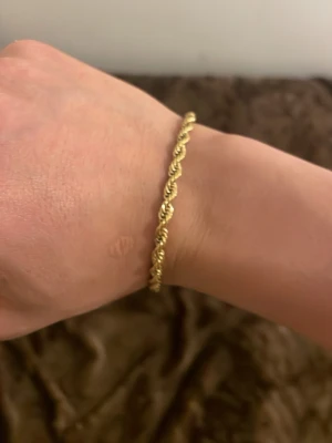 Guldtonat tvinnat armband - Snyggt armband i guldtonad metall med tvinnad design. Lätt att matcha och har ett smidigt lås. Perfekt accessoar för dig som gillar stilrena detaljer och enkel elegans.