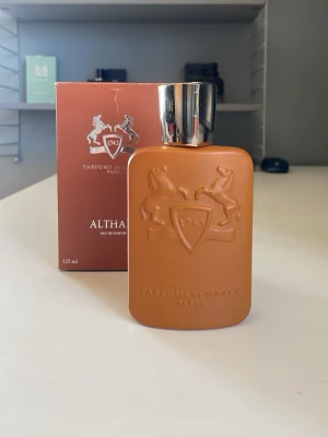 Parfums de Marly Althaïr EdP 125ml - Lyxig parfym från Parfums de Marly, modellen Althaïr. Flaskan är matt brun med silverfärgat lock och har ett elegant reliefmönster med två hästar och en sköld. Förpackningen matchar flaskans färg och design. Innehåller 125 ml Eau de Parfum. Korken fastnar tyvärr inte och har gott sönder. Men sprayen funkar precis som vanligt. Men med tanke på detta säljer jag den till ett mycket fördelaktigt pris. Skriv vid minsta fundering🤗