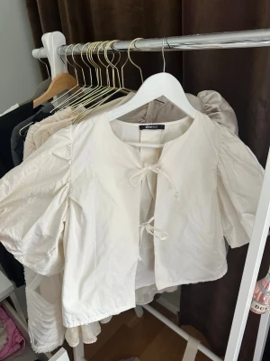 Vit puffärmad blus från Gina Tricot - Söt vit blus från Gina Tricot med puffiga korta ärmar och två knytband framtill. 