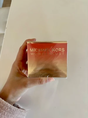 Michael Kors Wonderlust parfym 50ml - Michael Kors Wonderlust Eau de Parfum i en lyxig förpackning med guld och persikofärgade toner. Flaskan rymmer 50 ml och doften är känd för sin fräscha, blommiga och varma karaktär. Perfekt för dig som gillar exklusiva och moderna parfymer.