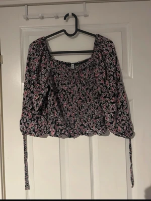 Blommig topp  - Supersöt blommig tröja samt knytband vid ärmsluten som ger en extra charmig detalj. Perfekt för dig som vill ha en romantisk och trendig topp till sommaren (ifrån new yorker) 