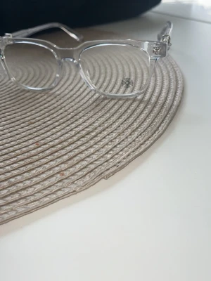 Transparenta solglasögon med silverdetaljer - Snygga solglasögon med transparent båge och rektangulär form. Sidorna har coola silverdetaljer som ger en unik touch. Perfekta för dig som vill sticka ut med en modern och stilren look.