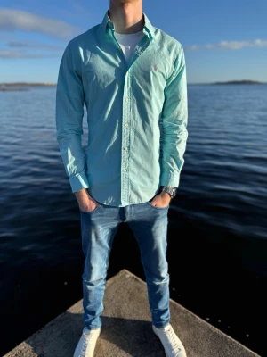 Ljusblå skjorta från Ralph Lauren - Snygg ljusblå skjorta från Ralph Lauren med klassisk krage och knappar framtill.  Perfekt till jeans eller chinos för en clean och stilren look. Storlek M och pris 379kr