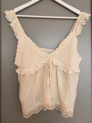 Beige virkad/spets topp - Supersöt beige linnetopp med virkade detaljer och volangkant. Perfekt topp för sommaren då den är luftig och supersöt!