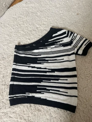 Svartvit oneshoulder stickad topp - Säljer en unik stickad topp one shoulder i svart och vitt med grafiskt randigt mönster. 