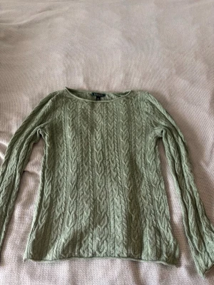 Grön kabelstickad tröja Lauren Ralph Lauren - Säljer en kabelstickad tröja från Lauren Ralph Lauren i ljusgrön nyans. Tröjan har rund halsringning och långa ärmar, stickad i ett klassiskt flätmönster. Perfekt för dig som gillar stilrena och tidlösa plagg.