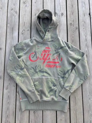 Superdry surf hoodie - En fet superdry suft hoodie med palmblad över tröjan